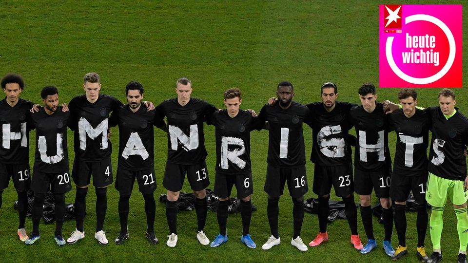 Die Fußball-Nationalmannschaft steht mit "Human Rights" auf schwarzen Shirts Arm in Arm auf dem Rasen