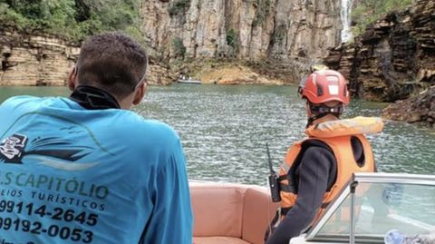 Brasilien: Zwei Menschen blicken von einem Boot aus auf die Felswand, die auf den See heruntergestürzt ist.