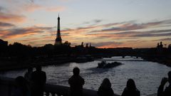 Touristen stehen in Paris auf einer Brücke über die Seine und fotografieren den Eiffelturm bei Sonnenuntergang