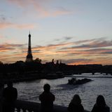 Touristen stehen in Paris auf einer Brücke über die Seine und fotografieren den Eiffelturm bei Sonnenuntergang