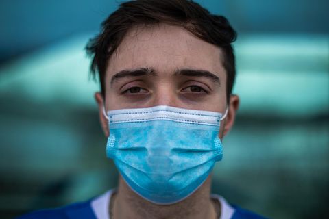 Junger Mann mit OP-Maske schaut mit erschöpften Augen in die Kamera