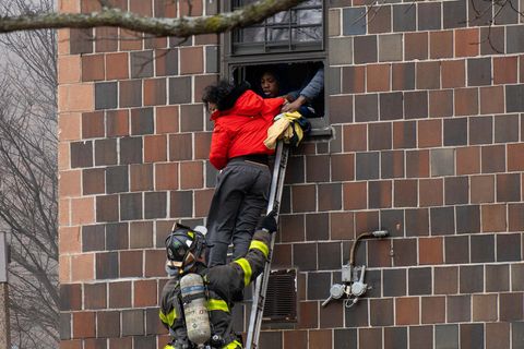 Mithilfe der Feuerwehr und einer Leiter flüchten Anwohner durch ein Fenster aus ihrem brennenden Wohnhaus in New York