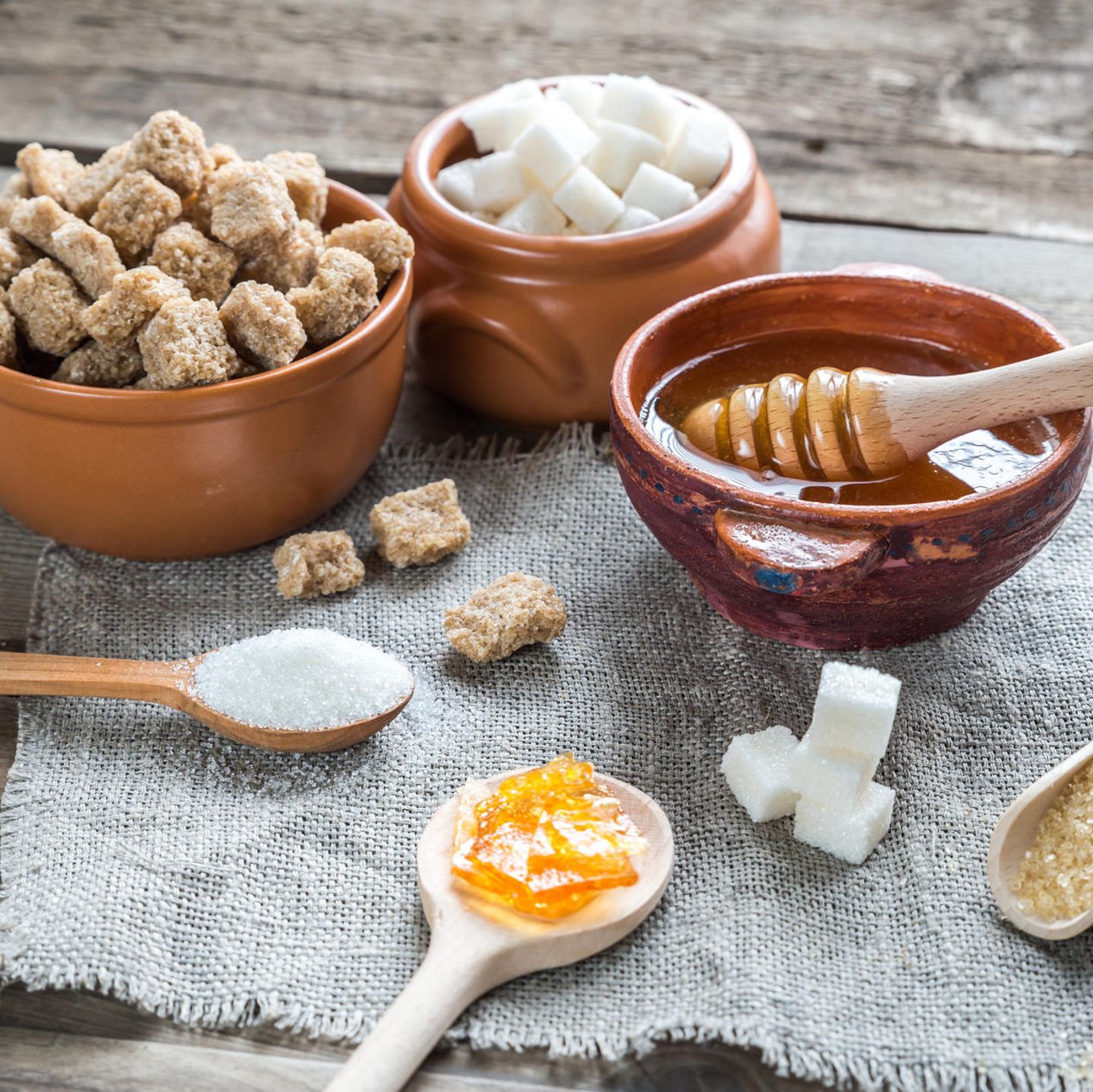 Ein Tisch mit braunem Zucker, weißem Zucker, Honig, Würfelzucker etc.