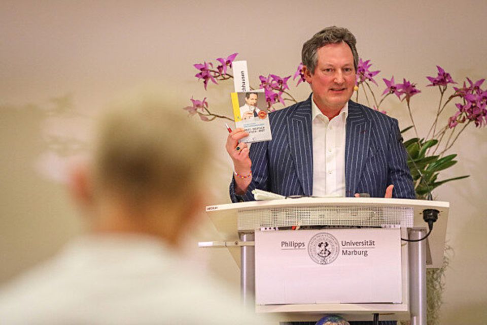 Eckart von Hirschhausen steht vor lilafarbenen Blüten