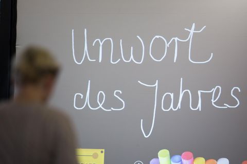 Die Worte "Unwort des Jahres" sind mit Schreibschrift an eine Tafel gemalt