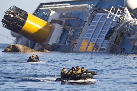 Schlauchboote mit Besatzung vor einem gekenterten Kreuzfahrtschiff