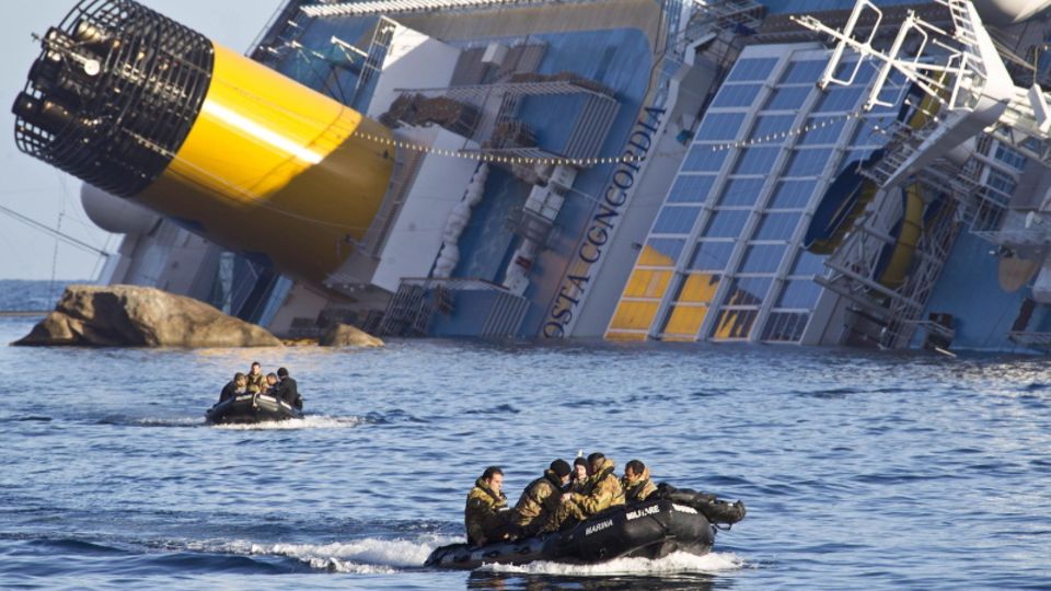 Schlauchboote mit Besatzung vor einem gekenterten Kreuzfahrtschiff
