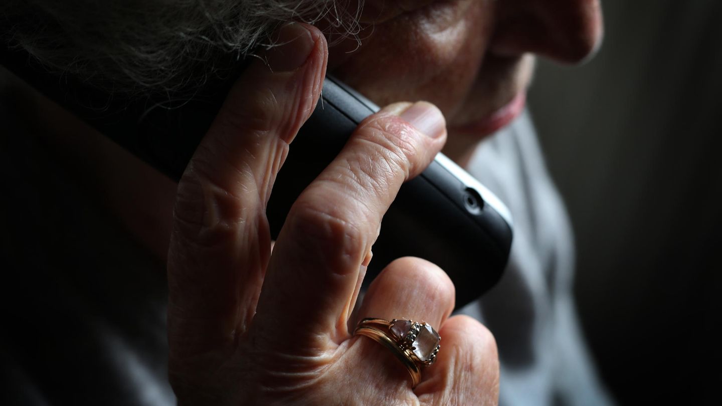 Eine Seniorin hält ein Telefon ans Ohr