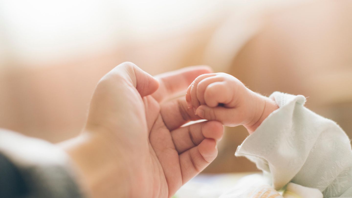 Die Hand eines Babys umgreift den Finger eines Erwachsenen
