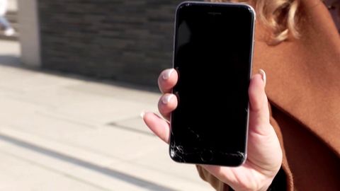 Reparatur notwendig: Eine Frau hält ein kaputtes Smartphone in der Hand