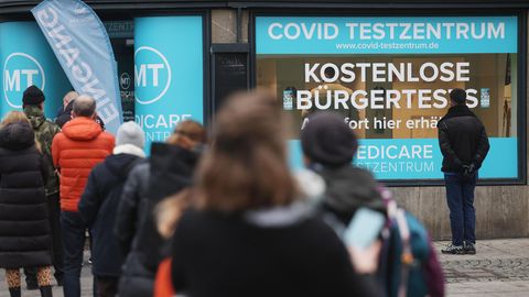 Menschen stehen vor einem Corona-Testzentrum in Köln in der Schlange.