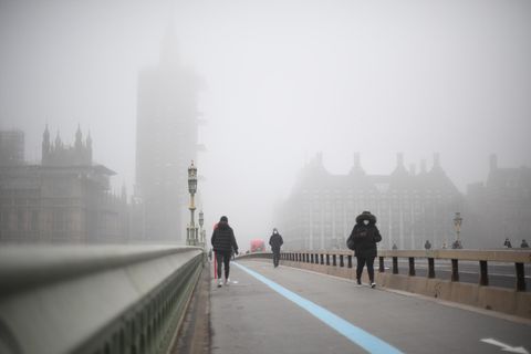 Passanten auf einer Brücke in London, die Luft wirkt neblig