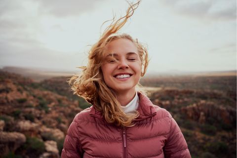 Eine junge Frau lächelt während der Wind ihr die Haare um den Kopf bläst