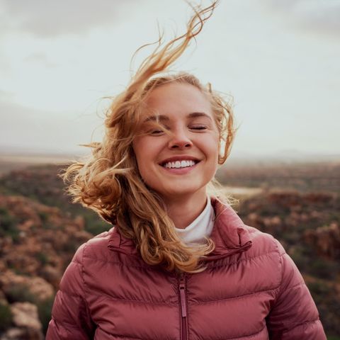 Eine junge Frau lächelt während der Wind ihr die Haare um den Kopf bläst