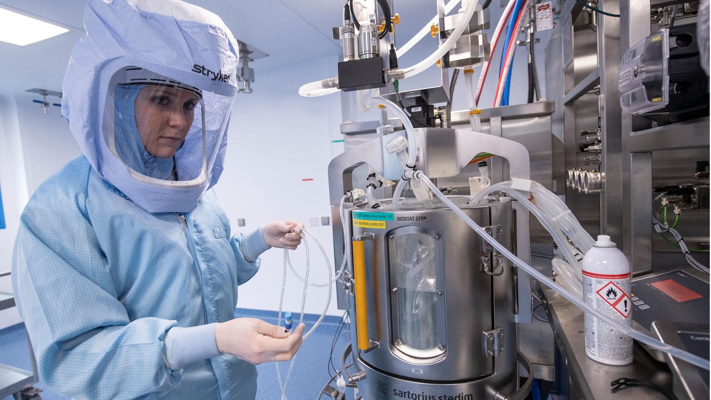 Eine Laborantin trägt einen blauen Ganzkörper-Schutzanzug