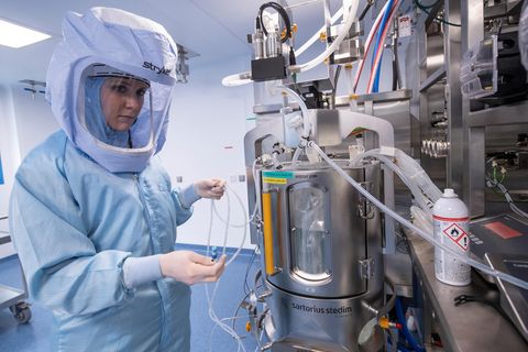 Eine Laborantin trägt einen blauen Ganzkörper-Schutzanzug