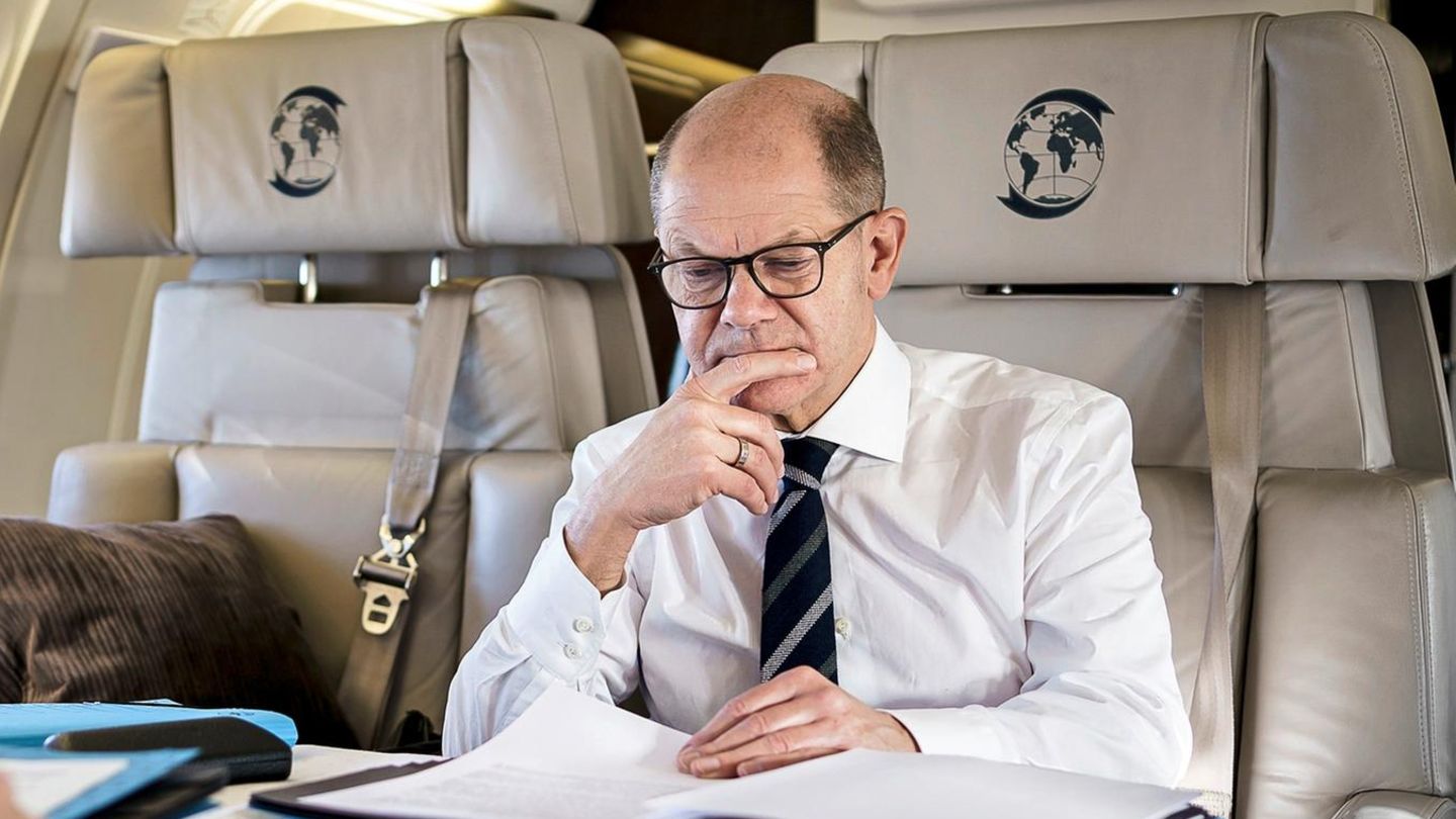 Olaf Scholz geht in einem Flugzeug Unterlagen durch