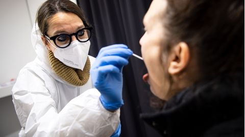 In einem Bremer Testzentrum nimmt eine Mitarbeiterin den Abstrich für einen Coronavirus-Test