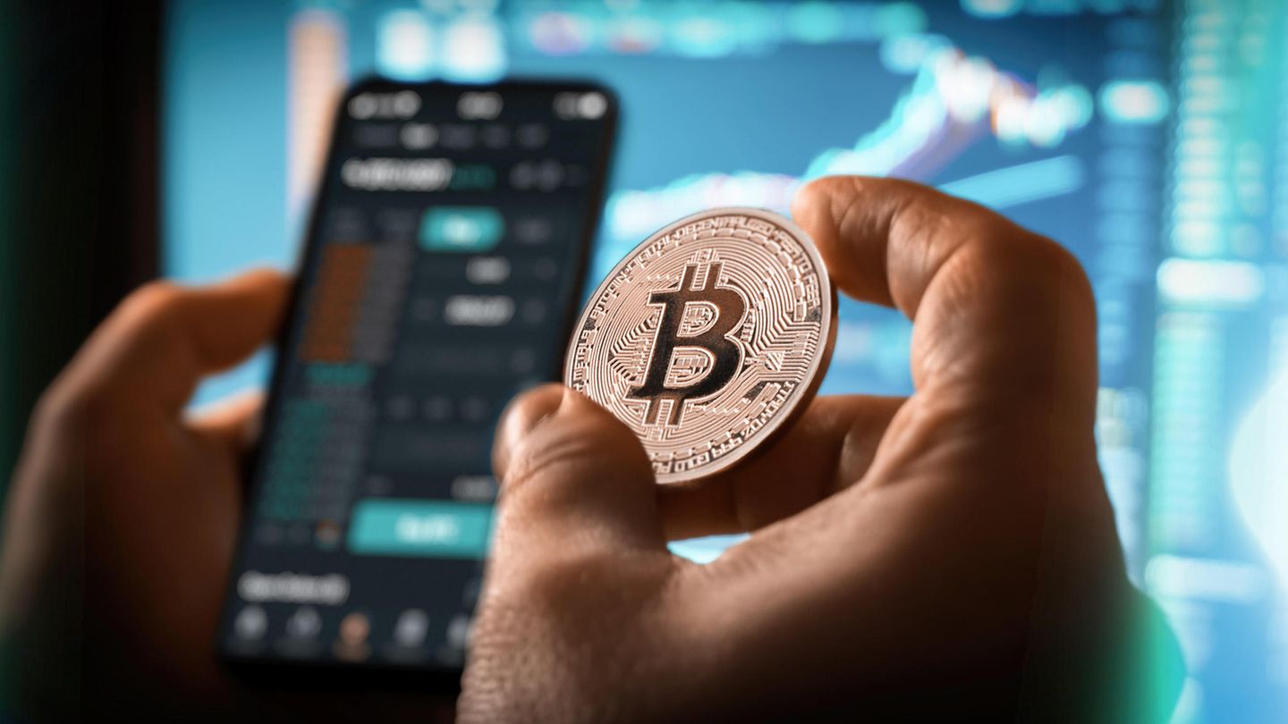 Eine Person hält einen Bitcoin in der Hand und tätigt einen Handel mit Kryptowährungen
