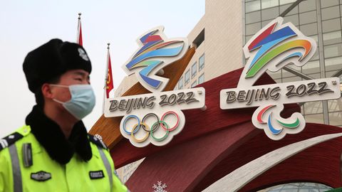 Ein Sicherheitsbeamter vor den Logos der Olympischen Winterspiele in Peking