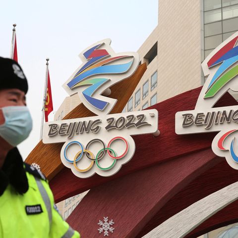 Ein Sicherheitsbeamter vor den Logos der Olympischen Winterspiele in Peking