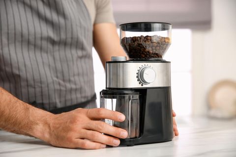 Mann mit elektrischer Kaffeemühle in der Küche