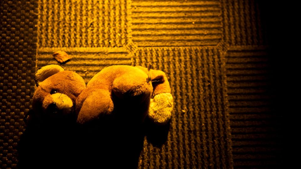 Teddybar liegt auf dem Boden.
