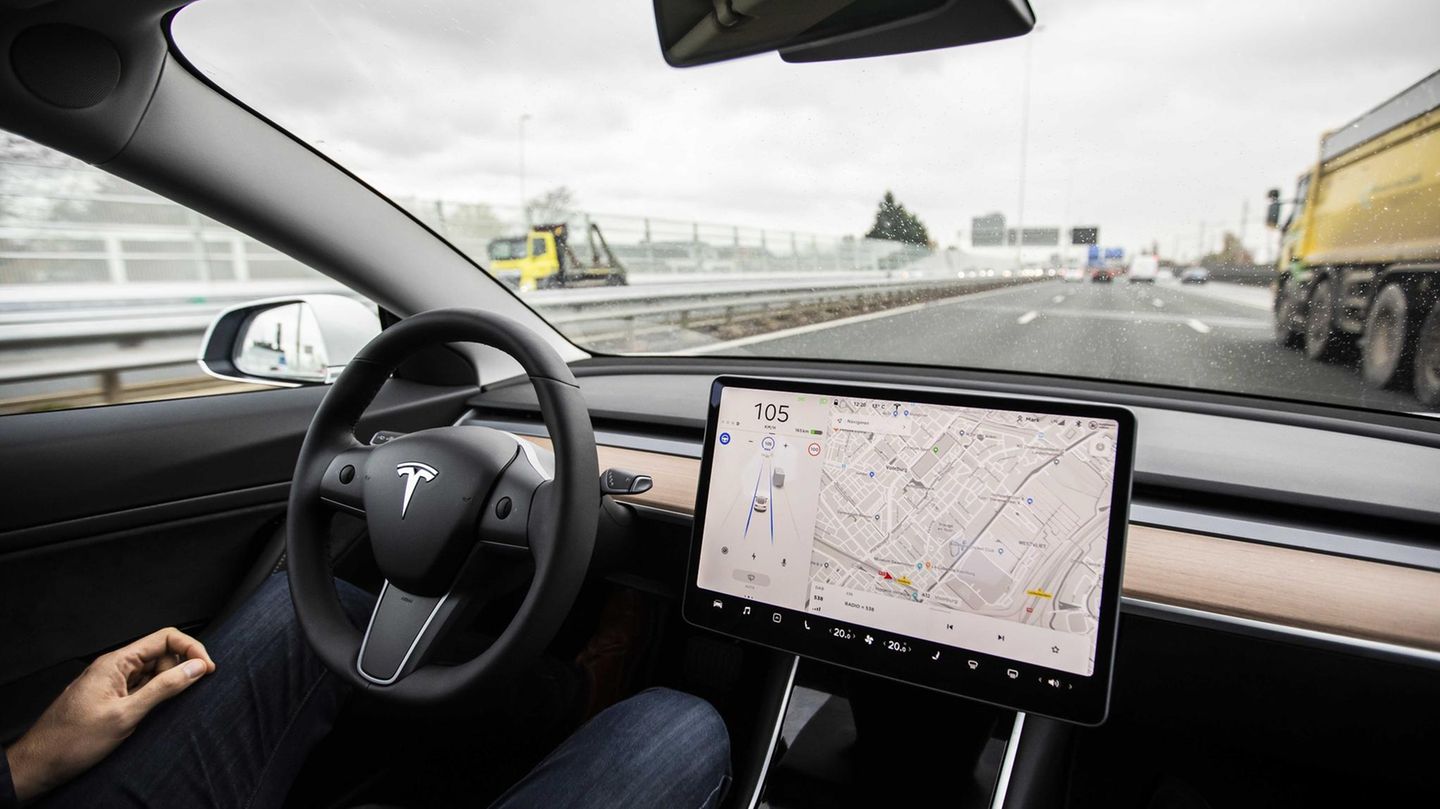 Ein Mann sitzt am Steuer eines Tesla-Autos und hat seine Hände während der Fahrt nicht am Lenkrad.