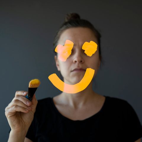 Eine Frau malt auf den Spiegel ein Smiley, der ihr Gesicht verdeckt