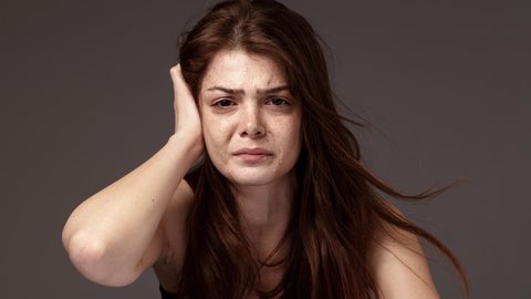 Eine Frau weint und streicht sich durchs Haar