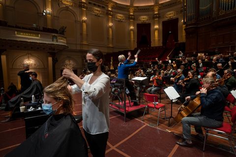 Menschen lassen sich während einer Probe im Konzertsaal in den Niederlanden die Haare schneiden