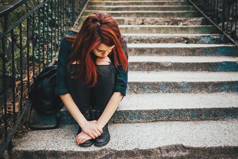 Junges Mädchen sitzt allein auf einer Treppe