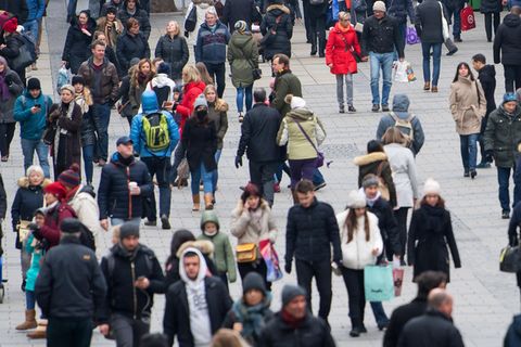 Passanten gehen durch eine Fußgängerzone in Deutschland.