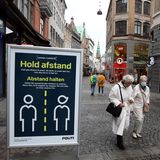 "Hold afstand" und "Abstand halten" steht auf einem Schild in einer Straße in Kopenhagen. Zwei weißhaarige Damen gehen vorbei