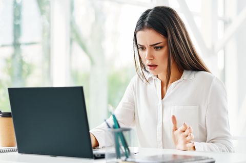 Frau schaut geschockt auf ihren Laptop