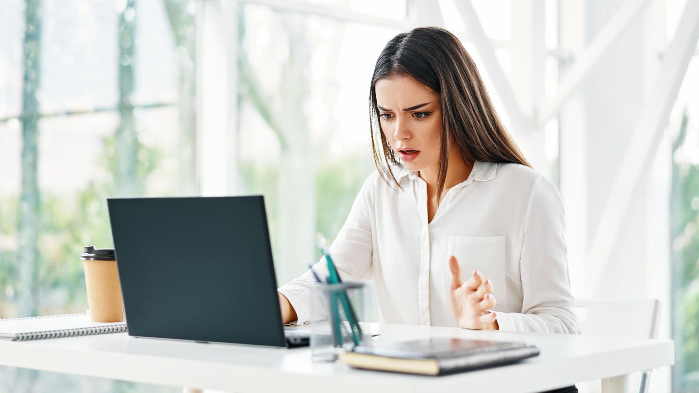 Frau schaut geschockt auf ihren Laptop