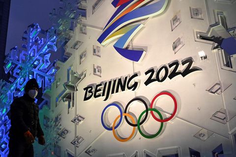 Ein Mann steht vor dem Logo der olympischen Winterspiele 2022 in Peking