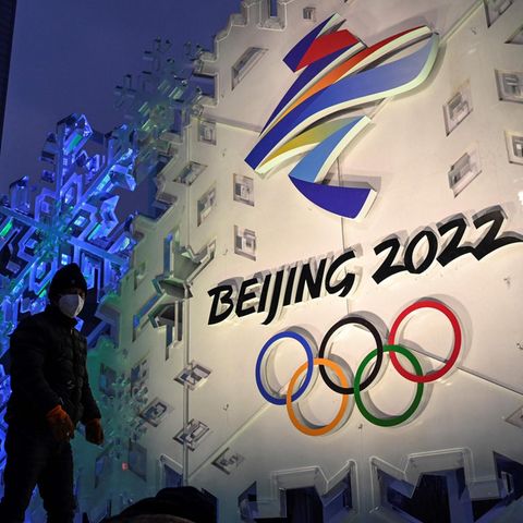 Ein Mann steht vor dem Logo der olympischen Winterspiele 2022 in Peking