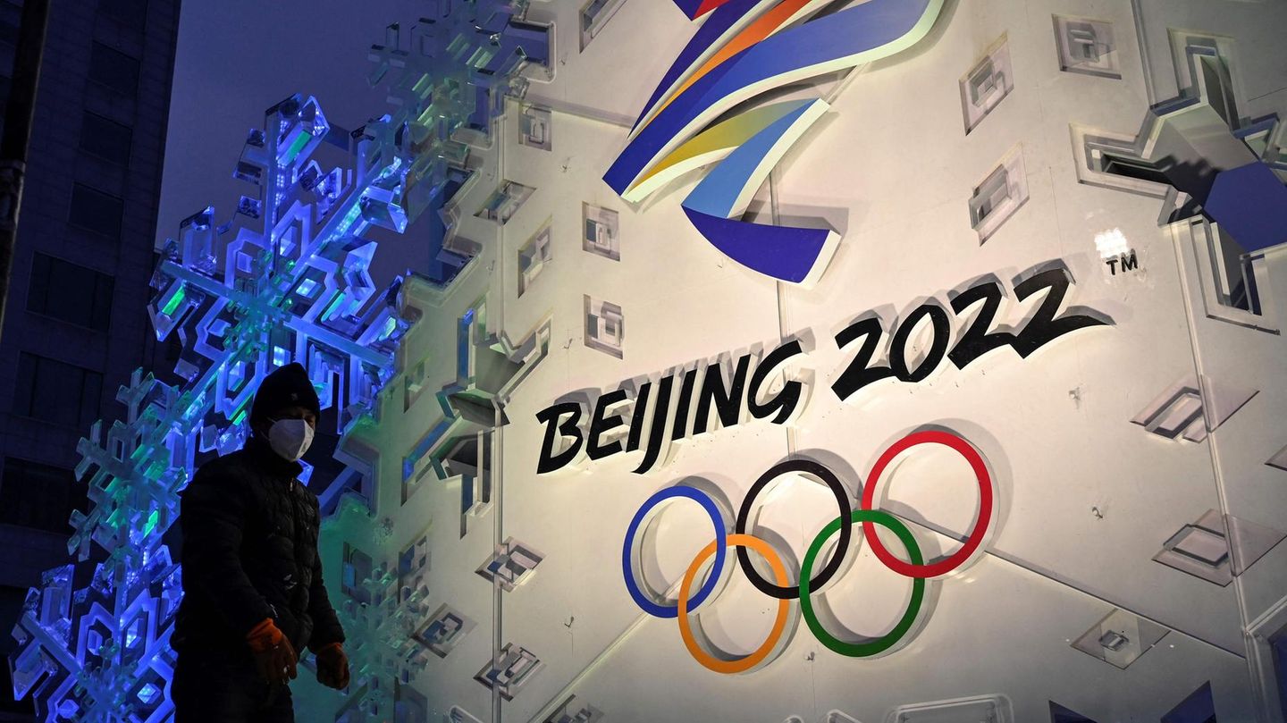 Ein Mann steht vor dem Logo der olympischen Winterspiele 2022 in Peking