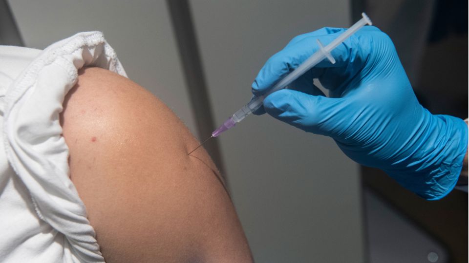 Debatte um Impfpflicht: Eine Impfnadel wird in einen Oberarm gepiekst.