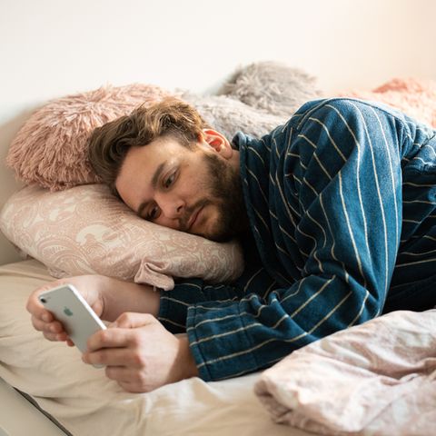 Benedikt Herber liegt mit seinem Handy in der Hand im Bett