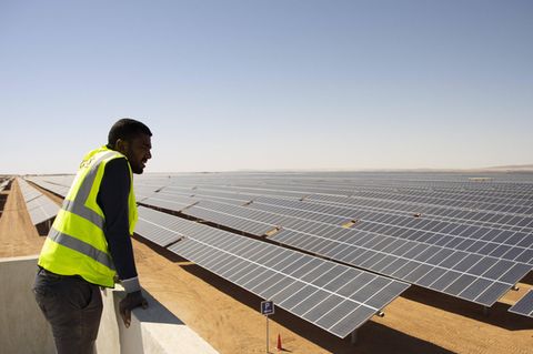 Ein Arbeiter schaut auf eine Photovoltaik-Freiflächenanlage in der ägyptischen Wüste bei Aswan