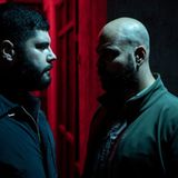 Zwei Männer in einem dunklen raum vor einem roten Hintergrund