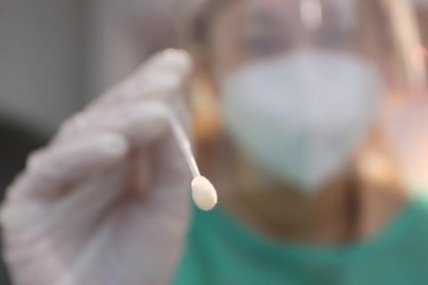 Corona: Eine Frau nimmt in einer Teststation mit einem Tupfer einen Abstrich für einen PCR-Test