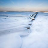 Buhne in Wind und Schnee: Langzeitbelichtung am winterlichen Ostseestrand.