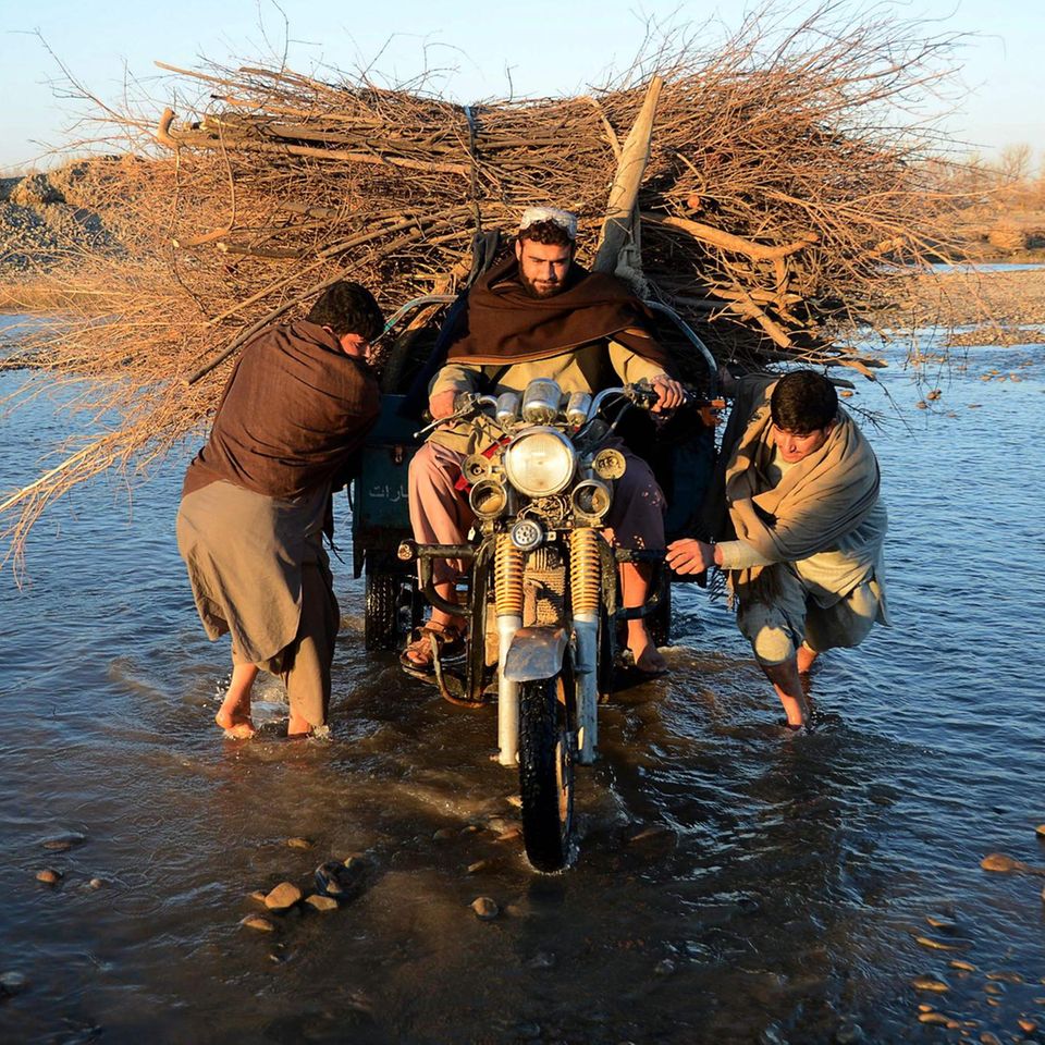 Kandahar, Afghanistan. Manchmal muss man Wege gehen, die sonst keiner geht. Nach diesem Motto fährt ein Mann mit seinem schwer beladenen Motorrad über den Fluss Arghandabin in der Nähe der Stadt Kandahar. Zwei Männer helfen ihm.