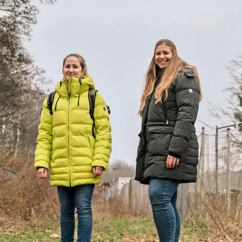 Zwei junge Frauen stehen vor einem Zaun mit Plakat "Bremer Tafel e.V."