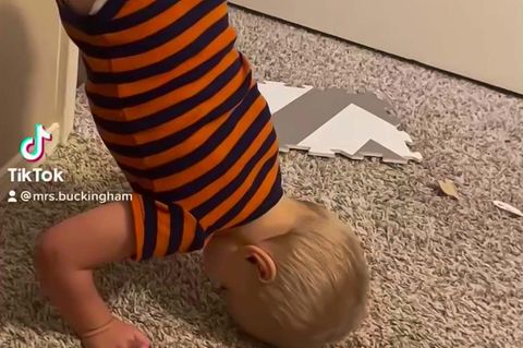 Kleinkind ohne Beine macht einen Handstand am Boden