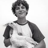 Ein junger Mann mit Locken und einer Gans auf dem Arm