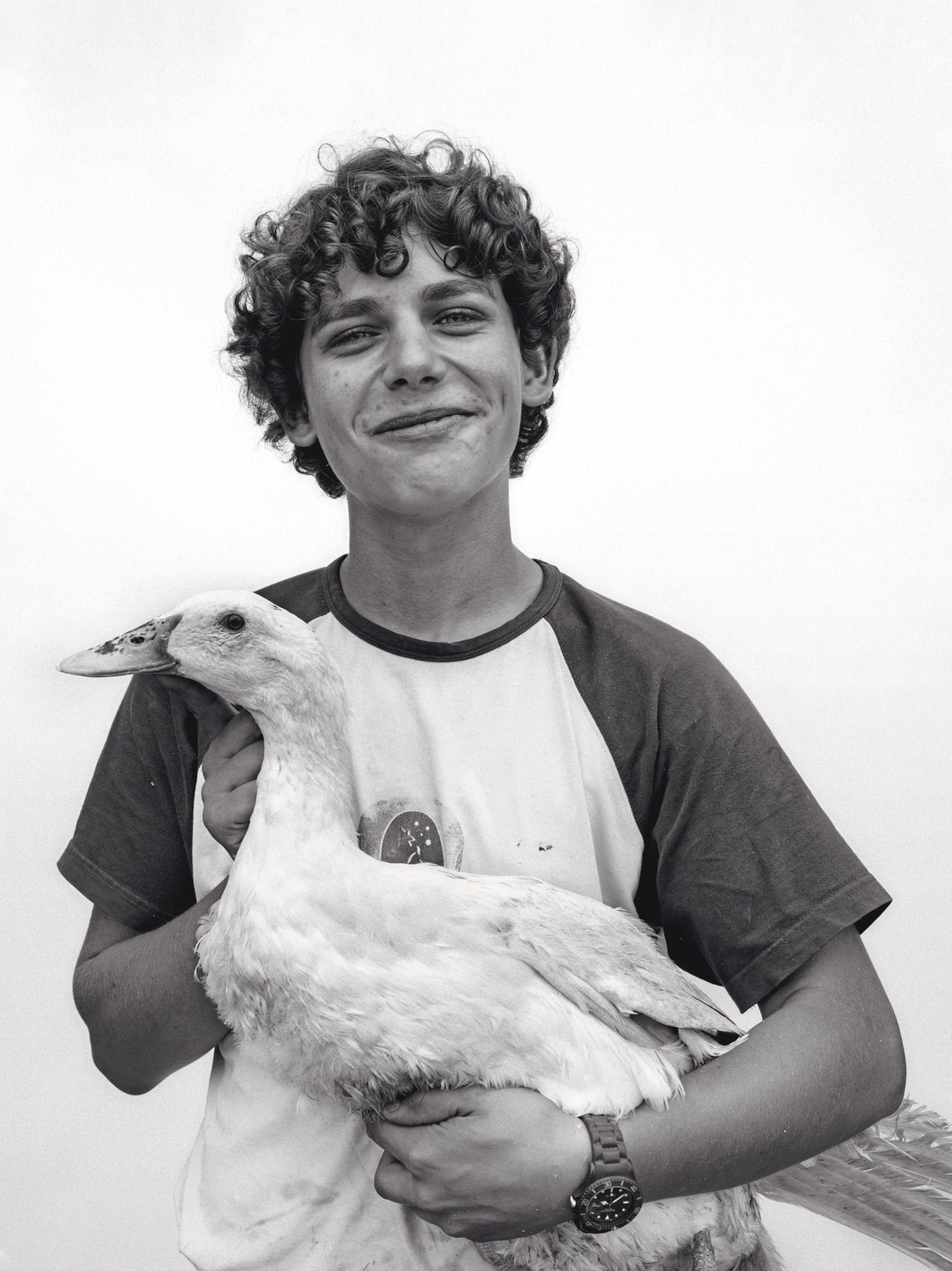 Ein junger Mann mit Locken und einer Gans auf dem Arm